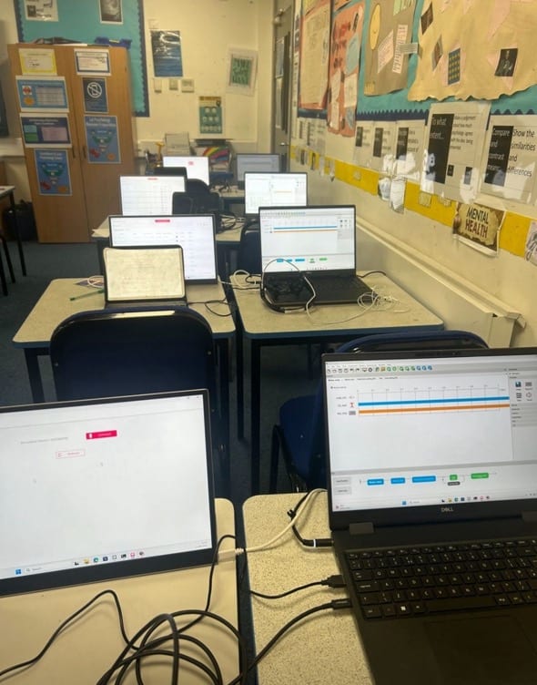 A school classroom set up for a workshop, with laptops on the desks showing the recording software